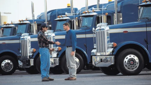 Row of semi-trucks with two people shaking hands